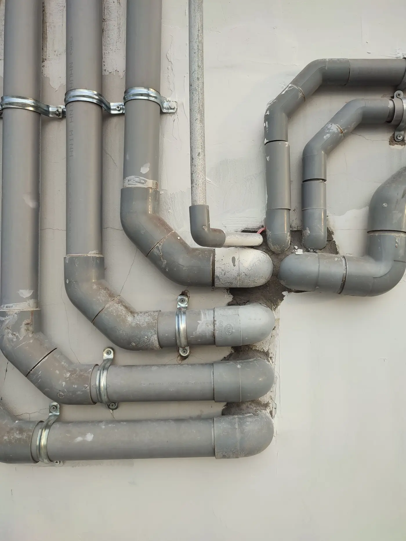 Grey PVC drain pipes and bends mounted on an outside wall