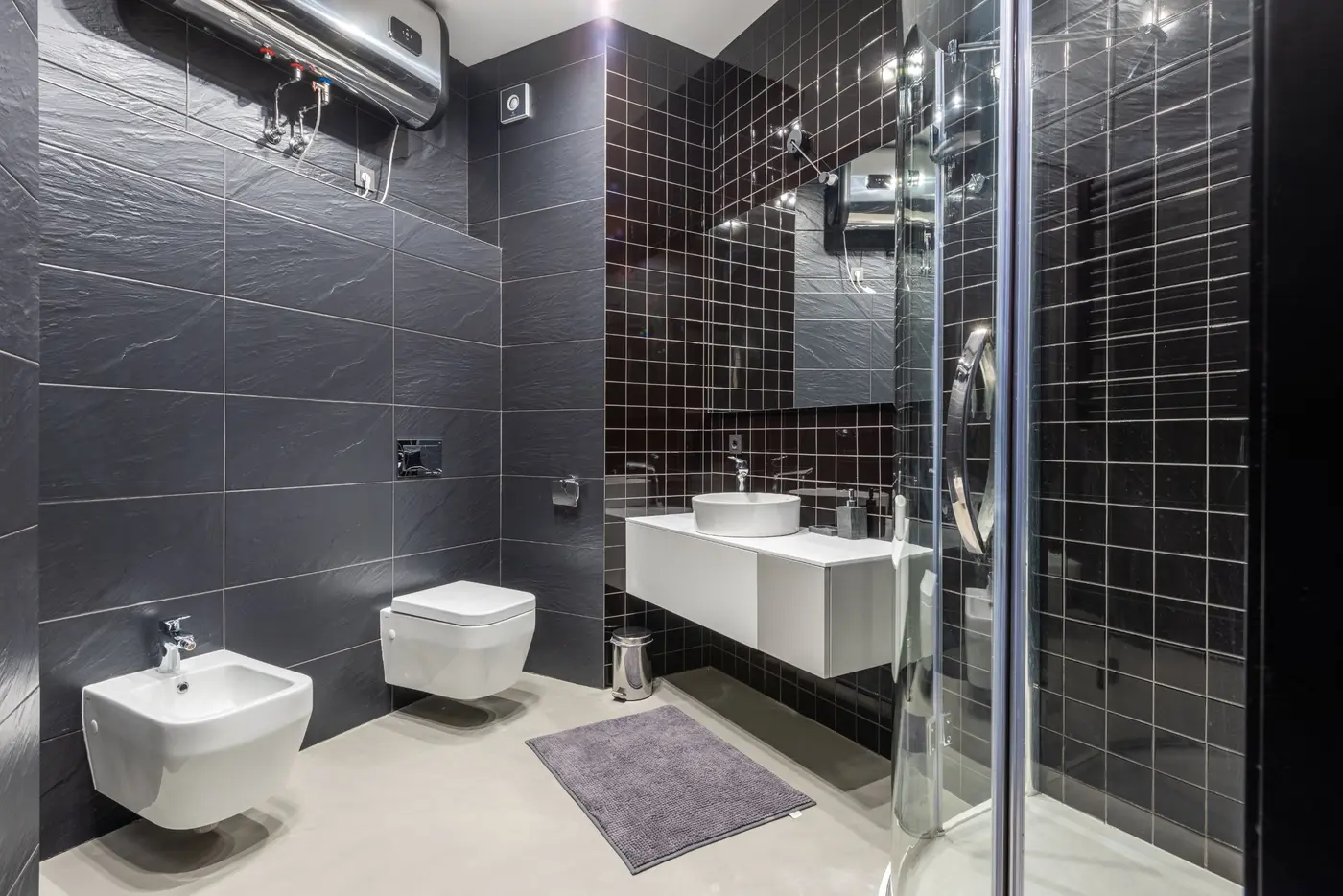 Wall-mounted geyser installed above a modern bathroom with dark tiles
